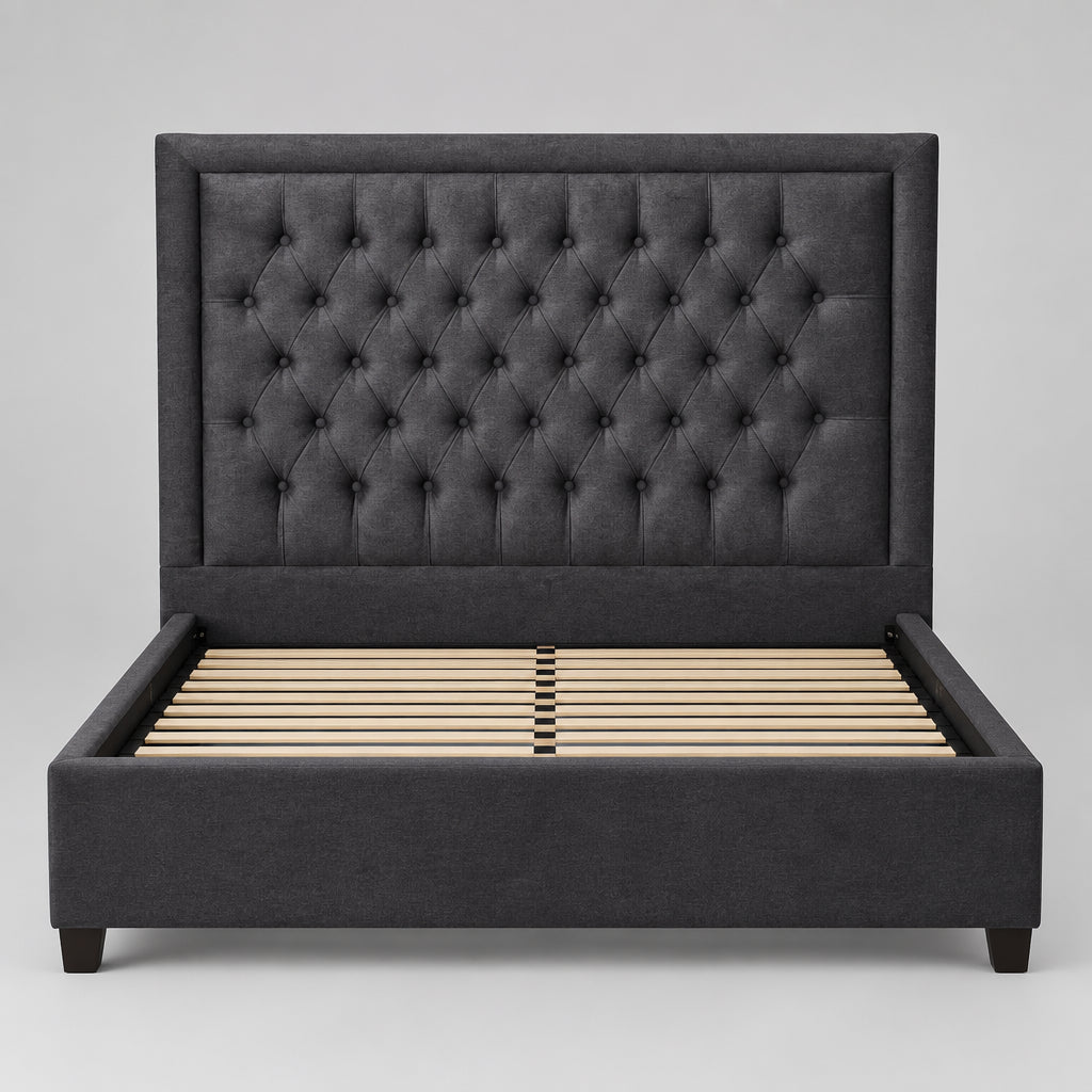 A dark gray tufted velvet headboard leaning against a plain white wall.