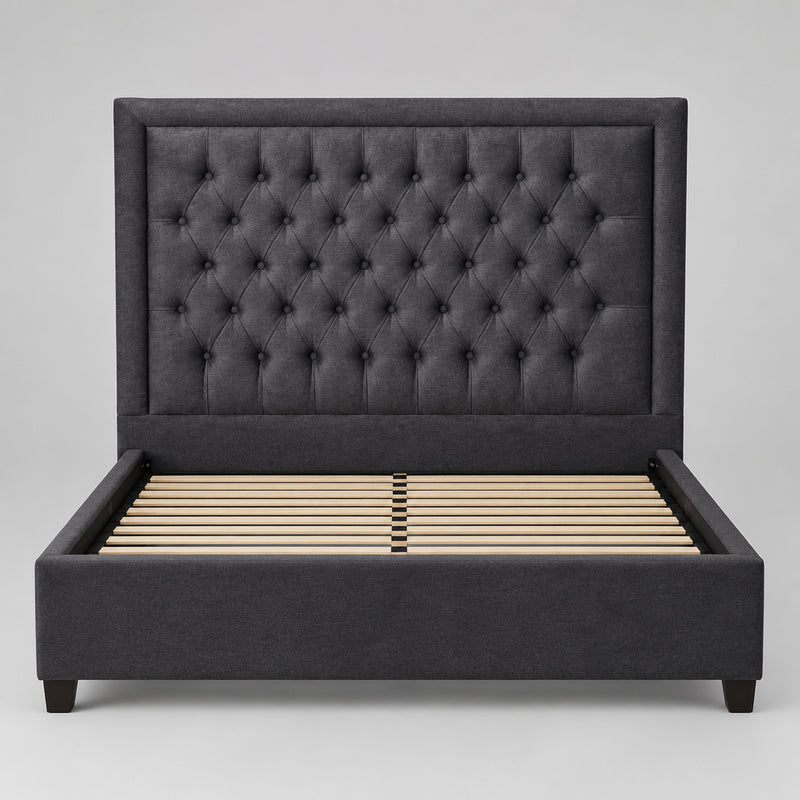 A dark gray tufted velvet headboard leaning against a plain white wall.