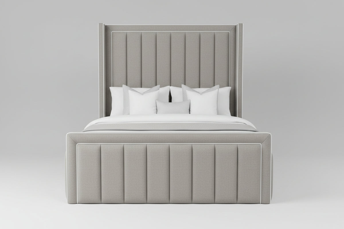 A modern upholstered bed with a tall channel-tufted headboard and matching footboard, dressed in white bedding and a gray throw blanket, shown in a minimalist bedroom setting.