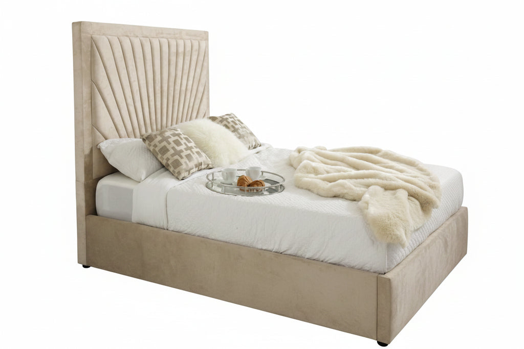 A modern upholstered bed with a tall, pleated beige headboard and matching footboard, styled with white bedding, patterned pillows, and a cream throw blanket in a bright bedroom.