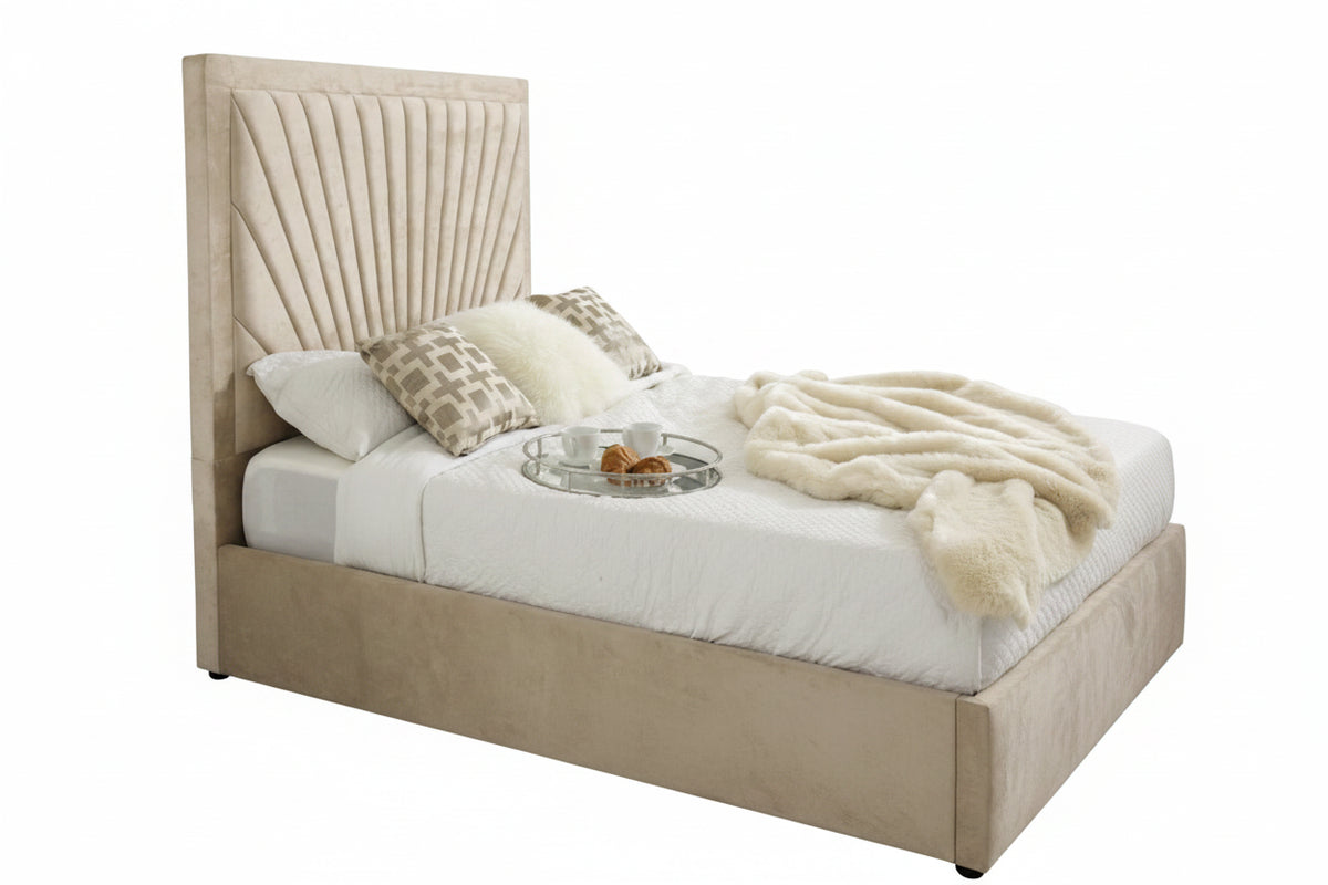 A modern upholstered bed with a tall, pleated beige headboard and matching footboard, styled with white bedding, patterned pillows, and a cream throw blanket in a bright bedroom.